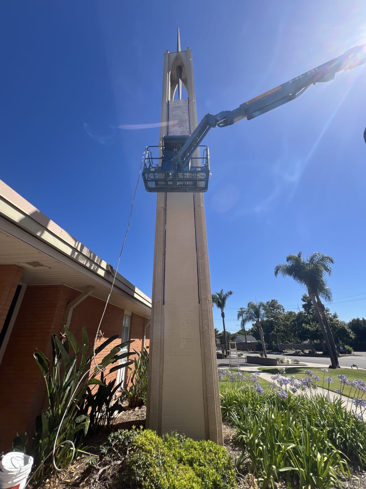 Dan's Handyman repainting a church steeple from a lift
